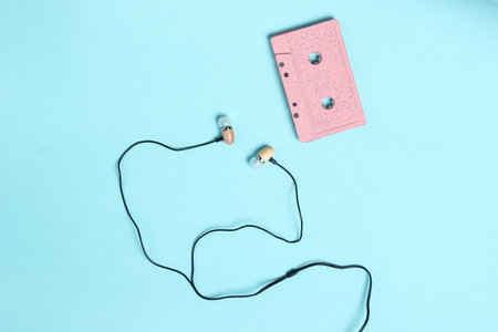 Vacuum earphones on blue pastel background. Retro media, music lover, 80s. Top view, flat lay