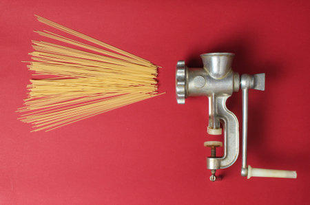 Vintage meat grinder and pasta on red background, top view, minimalismの写真素材