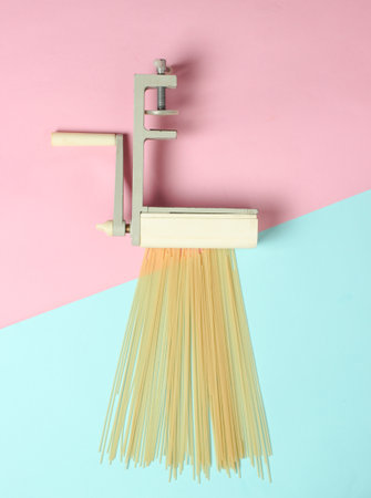 Retro device for manual cutting pasta on a pastel background. Top view. Minimalism