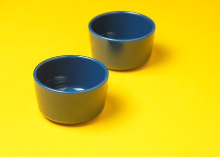 Two blue enamel bowls on yellow background.の写真素材