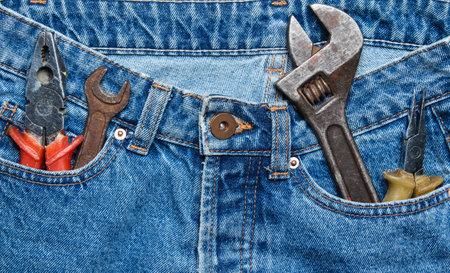 Work tool in the pocket of blue jeans. Pliers, wrench, adjustable wrench