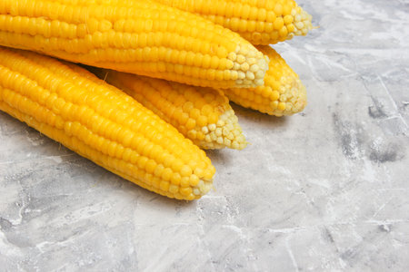 Ripe boiled corn on a gray concrete table, top view