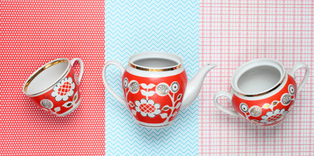 Retro cups and teapot with red patterns on tablecloth. Top viewの写真素材