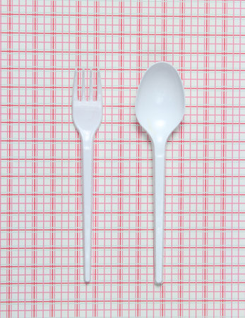 Plastic spoon and fork on a tablecloth. top view