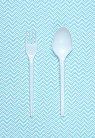 Plastic spoon and fork on blue tablecloth. top view