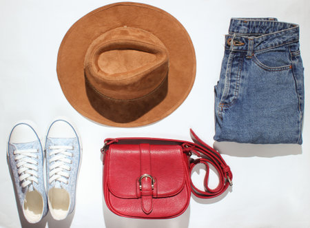 Women's clothing, shoes, accessories on a white background. Sneakers, hat, jeans, bag. Photo with shadows. Top Viewの写真素材