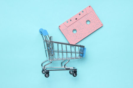 Retro audio cassette in the shopping trolley on blue background. Top view