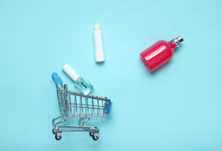 Perfume bottle, lipstick in a shopping cart on a blue pink pastel background. minimalism, the concept of beauty, accessoriesの写真素材