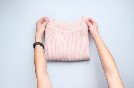 Hands fold knitted sweater on a gray background. Conceptual photo. Top viewの写真素材