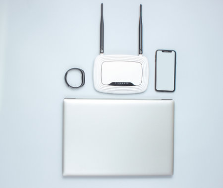 Laptop, Wi-Fi router with antennas, smart phone, smart watch on a gray background. Online work,...