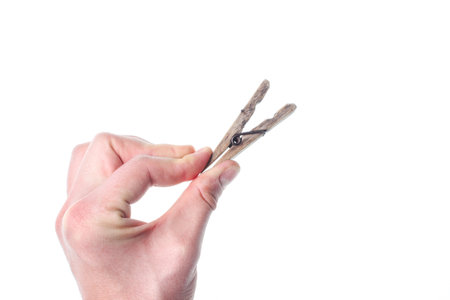 Hand squeezes the wooden clothespin isolated on whiteの写真素材