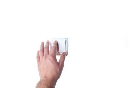 Hand presses a light switch isolated on white backgroundの写真素材