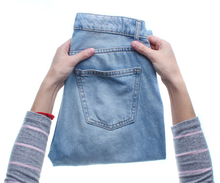 Hands folding jeans isolated on white background. Top view.の写真素材