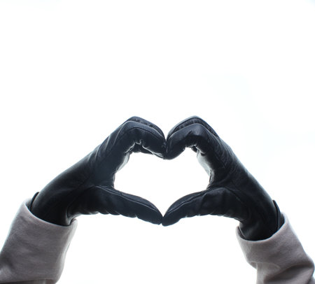 Female hands with leather gloves show a heart sign with fingers isolated on white background.の写真素材