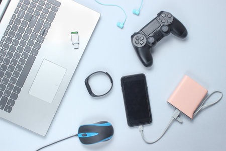 Modern gadgets and devices on a gray background. Laptop, power bank, earphones, smart bracelet,...