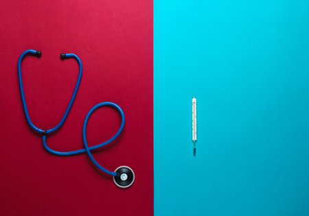 Stethoscope, thermometer on a red-blue background. Medical concept, top viewの写真素材
