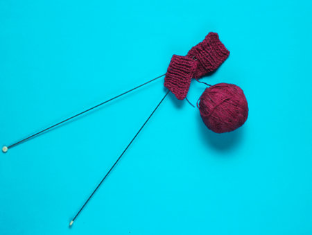 Knitting needles, thread balls, yarn on blue background.