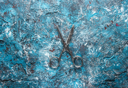 Old metal scissors on a blue concrete background