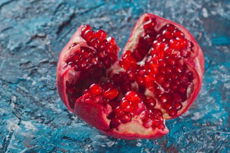 Ripe broken pomegranate on a blue concrete background