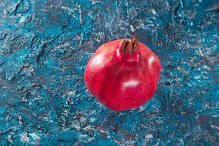 Ripe pomegranate on blue concrete backgroundの写真素材