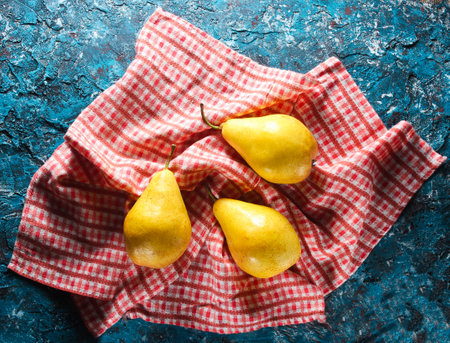 Three ripe pears on tablecloth on the blue concrete background. Top view.の写真素材