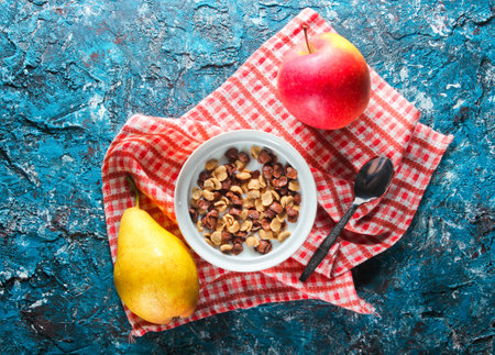 Quick breakfast cornflakes in milk, ripe pear, apple on the tablecloth. rustic style on blue concrete table. Top viewの写真素材