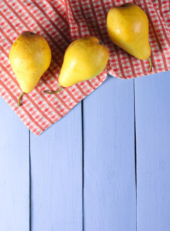 Three ripe pears with tablecloth on purple wooden background. Top view. Copy spaceの写真素材