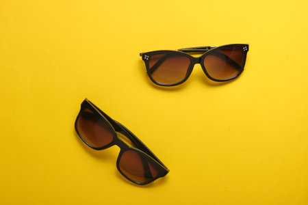 Two pairs of fashionable sunglasses on yellow background. From above, minimalismの写真素材