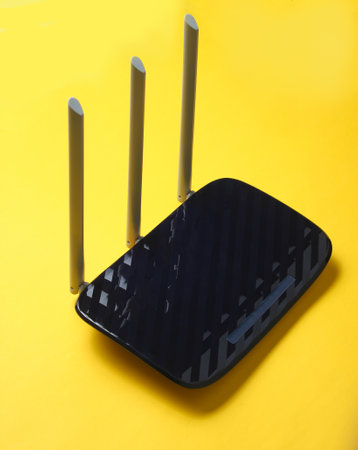Black Three-antenna router isolated on yellow background.
