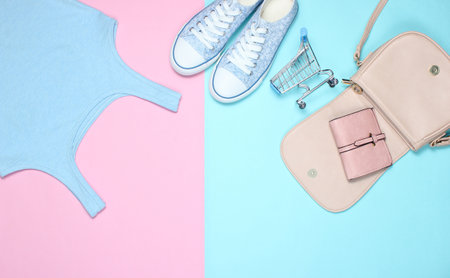 The concept of shopping. Women's clothing and accessories on pastel background. Sneakers, T-shirt,...