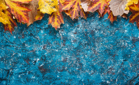 Creative frame with autumn leaves on blue concrete background. Top view