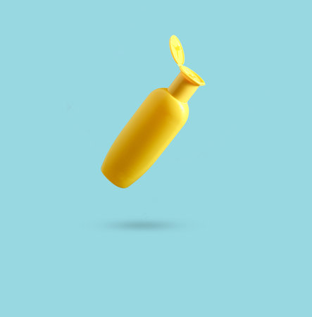 Yellow bottle of shower gel on blue background. Minimalism, conceptual photo, photo with shadow.の写真素材