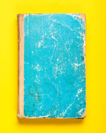 Old book with a blue shabby cover on a yellow backgroundの写真素材