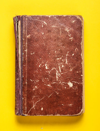 Old book with brown shabby cover on a yellow backgroundの写真素材