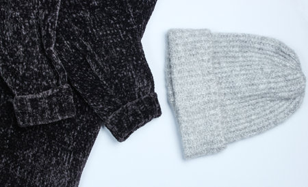 Velor black sweater and wool warm hat on a gray background. Top view.