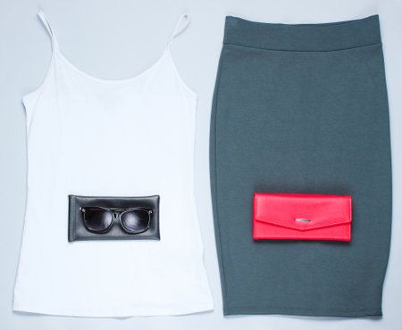 Women's fashion clothing and accessories on a gray background. Skirt, T-shirt, wallet, sunglasses. Flat Lay style.の写真素材