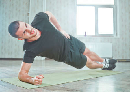 Healthy Sporty Man Doing Indoor Side Plank Exercise on Mat, Static Exerciseの写真素材