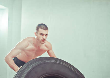 Concept functional training workout gym. Fitness man flipping tire wheel at gym