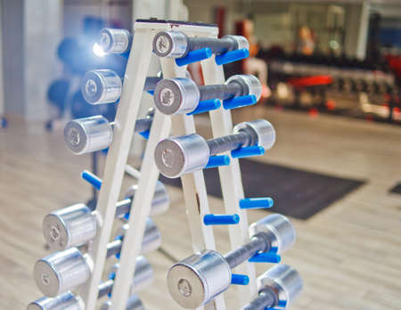 Rows of dumbbells in the gym. Dumbbell set. Many metal dumbbells on rack in sport fitness center