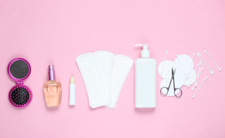 Women's beauty and hygiene products on pink pastel background. Perfume bottle, hygienic lipstick, pads, bottle cream,nail scissors. Flat lay style, top viewの写真素材