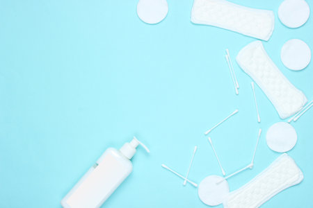Hygiene products on blue pastel background. Cotton pads, women's pads, bottle of cream, cotton ear sticks. Top view, flat lay, copy spaceの写真素材