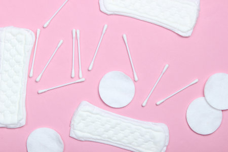 lat lay background with cotton branch, cotton pads, ear sticks, feminine pads on pink pastel backgroundの写真素材