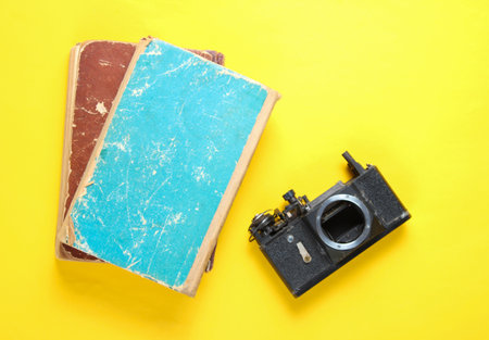 Disassembled old retro camera and old books on a yellow background. Minimalismの写真素材