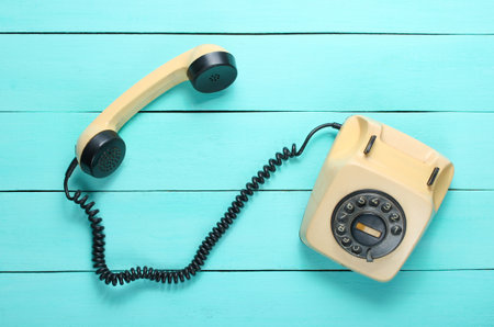 Pop culture attributes. Retro rotary telephone with a handset on a blue wooden table, top viewの写真素材