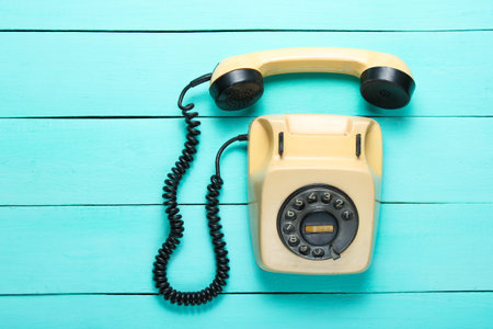 Pop culture attributes. Retro rotary telephone with a handset on a blue wooden table, top viewの写真素材