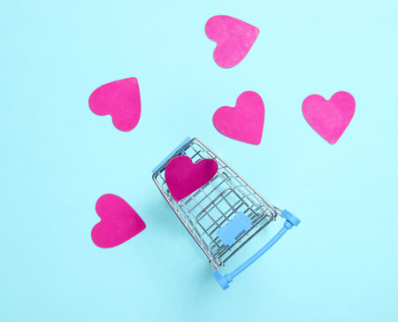 Mini shopping trolley, decorative hearts on blue background, top view, minimalism. Conceptual photo, loveの写真素材