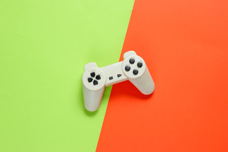 Retro style gamepad on green orange paper background, top view, minimalism