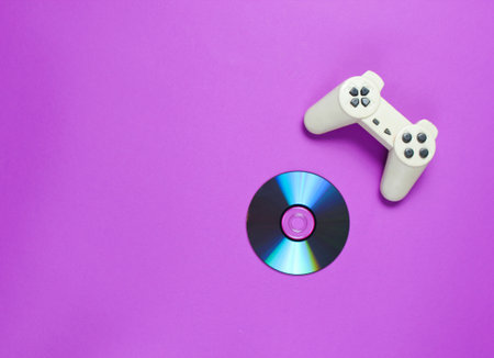 CD's disk, gamepad on a purple background. Retro gaming. Pop culture 80s. Top view, minimalismの写真素材