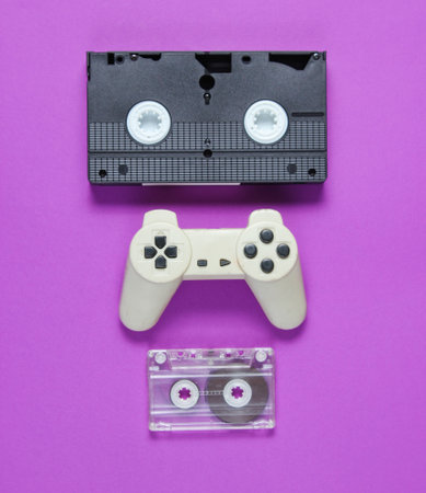 Pop culture attributes. audio cassette, retro gamepad, video tape on a purple background.の素材 [FY310162018493]