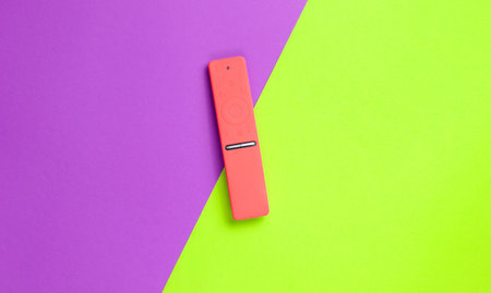 TV remote control in a red silicone case on a purple-green paper background. Minimalism, top viewの写真素材